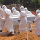 Health workers carry a body of a person killed by Ebola at a graveyard on the outskirts of Monrovia, Liberia, March 11, 2015. (Image: AP)